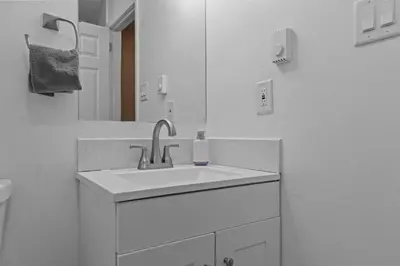 a white bathroom with a sink and a mirror at Evergreen Villa Poconos - Hot Tub, Fire Pit, Close to Kalahari, Great Wolf Lodge and Camelback in Tobyhanna