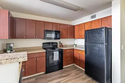 a kitchen with a black refrigerator and wooden cabinets at Landing Stunning 2BD Gym in New Haven