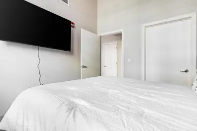 a bedroom with a white bed with a flat screen tv on the wall at Landing Stylish 1BD Gym Courtyard in New Haven
