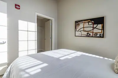 a white bedroom with a bed and a picture on the wall at Landing Stylish 1BD Gym Courtyard in New Haven