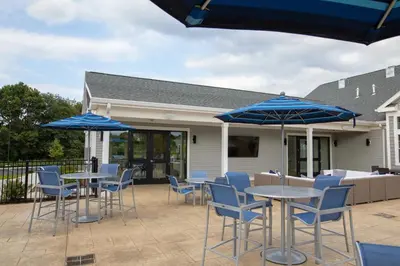 two tables and chairs with blue umbrellas on a patio at Landing Spectacular 2BD Yoga Studio Game Room in Vernon