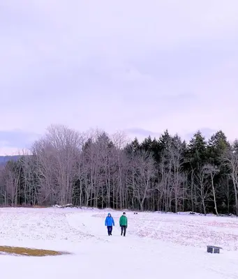 two people walking through a snow covered field at Skiing Close By! Firepit & Game Room in Prattsville
