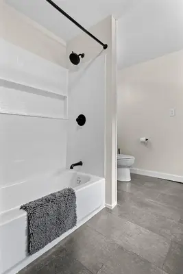 a white bathroom with a tub and a toilet at Skiing Close By! Firepit & Game Room in Prattsville