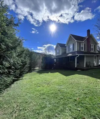 a house with a large yard with the sun in the sky at Charming Four Bedroom House in Tannersville