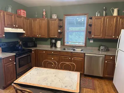 a kitchen with wooden cabinets and a table in it at Charming Four Bedroom House in Tannersville