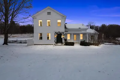 a white house with its lights on in the snow at Gorgeous Hudson Valley Farmhouse on 14 Acres home in Old Chatham