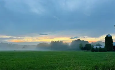 a foggy field with a sunrise in the background at Gorgeous Hudson Valley Farmhouse on 14 Acres home in Old Chatham