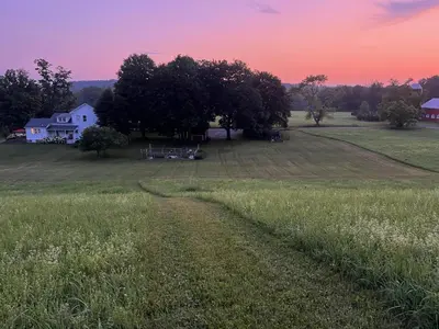 a field of grass with a house and a barn at Gorgeous Hudson Valley Farmhouse on 14 Acres home in Old Chatham
