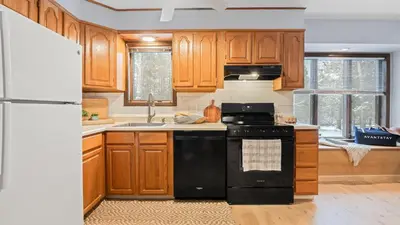 a kitchen with wooden cabinets and a black stove top oven at Catskills Mountain Home Near Windham w Fireplace Open Living Deer Run Lodge by AvantStay in Prattsville