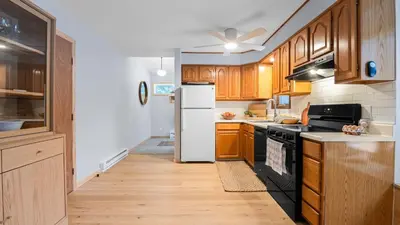 a kitchen with wooden cabinets and a white refrigerator at Catskills Mountain Home Near Windham w Fireplace Open Living Deer Run Lodge by AvantStay in Prattsville