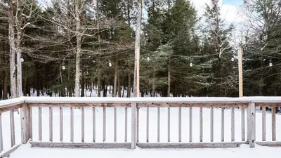 a fence covered in snow with trees in the background at Catskills Mountain Home Near Windham w Fireplace Open Living Deer Run Lodge by AvantStay in Prattsville