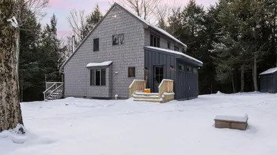 a gray house in the snow with trees at Catskills Mountain Home Near Windham w Fireplace Open Living Deer Run Lodge by AvantStay in Prattsville