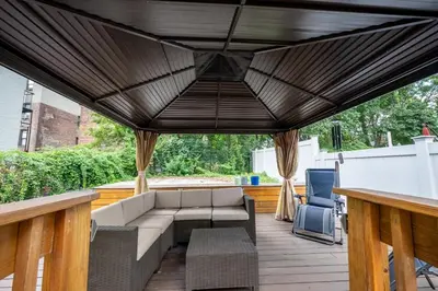 a covered patio with a couch and a table at Massive NYC House with Pool Table in Yonkers