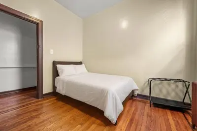 a bedroom with a bed with white sheets and a refrigerator at Massive NYC House with Pool Table in Yonkers