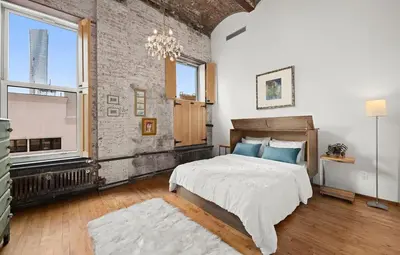 a bedroom with a large bed and a brick wall at Sun-Filled Luxury Historic 2 Bedrooms apto in New York