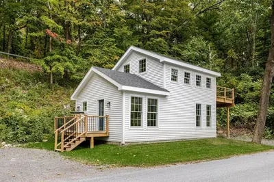 a small white house with a deck in the grass at Berkshire House in Hillsdale