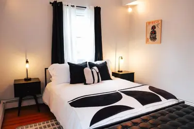 a bedroom with a black and white bed and a window at Hot Tub, 2 Blocks to Downtown Saugerties, Sleeps 8 in Saugerties