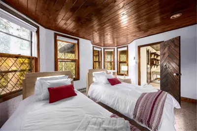 two beds sitting in a room with windows at Mansion of Belleayre Mountain! POOL, SAUNA, Game Room in Fleischmanns