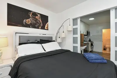 a bedroom with a large black bed and a kitchen at Cozy 1BR in Central Manhattan W Private Terrace in New York