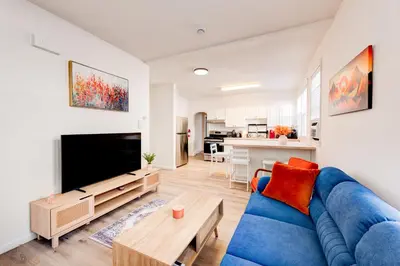 a living room with a blue couch and a tv at The Hamilton Elm in Teaneck