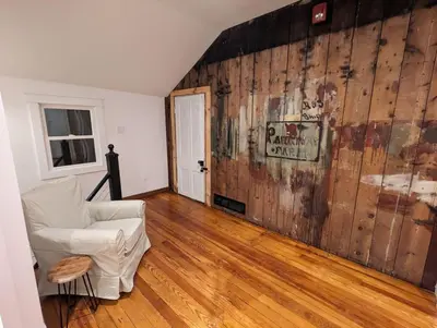 a living room with a white chair and a wooden wall at Carriage House Apartment Close to Legoland NY in Goshen