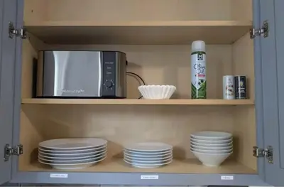 a cabinet with plates and a microwave in it at Cozy 3 Bedrooms Spacious Comfort in Orange