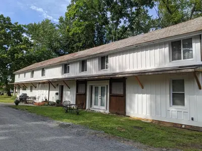 an old white house with a porch and a driveway at Historic Barn - 2 Bedroom Apartment Close To Legoland NY in Goshen