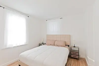 a white bedroom with a large bed and two windows at 17m to NYC,5 min to American Dream,2Parking Spaces in Carlstadt