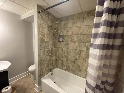 a bathroom with a bath tub and a toilet at Beach Apartment in Woodmont Milford 102 in Milford