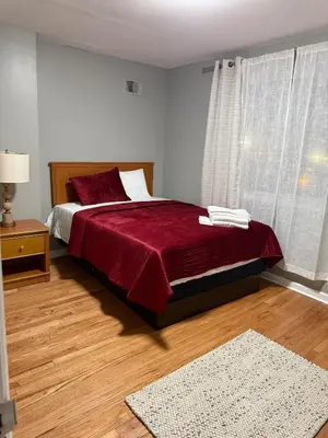 a bedroom with a bed with a red blanket and a window at Barnes Avenue near Yale in New Haven