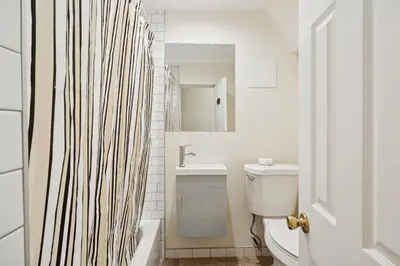 a white bathroom with a shower curtain and a sink at Heaven in Newark