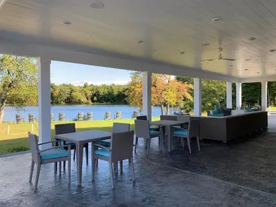 a pavilion with tables and chairs with a view of a lake at Landing Apartments - The Preserve at Great Pond in Windsor