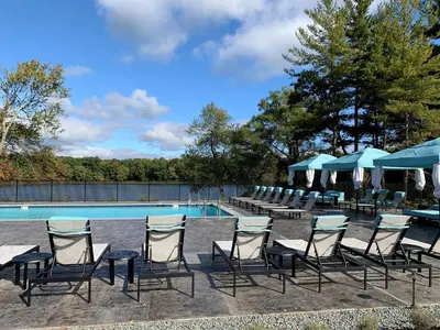 a group of chairs and tables next to a pool at Landing Apartments - The Preserve at Great Pond in Windsor