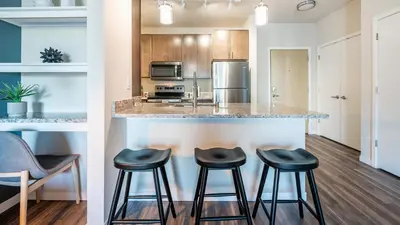 a kitchen with three stools at a counter in a kitchen at Landing Apartments - The Preserve at Great Pond in Windsor