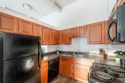 a kitchen with wooden cabinets and a black refrigerator at Landing Stylish 1BD Courtyard in Springfield