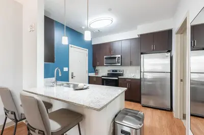 a kitchen with a counter with chairs and a refrigerator at Landing Beautiful Studio in South End Stratford in Stratford