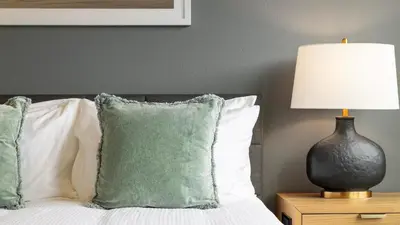 a bedroom with a bed with a lamp and pillows at Landing Apartments - Park South in Albany