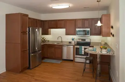 a kitchen with wooden cabinets and a stainless steel refrigerator at Landing Apartments - Park South in Albany