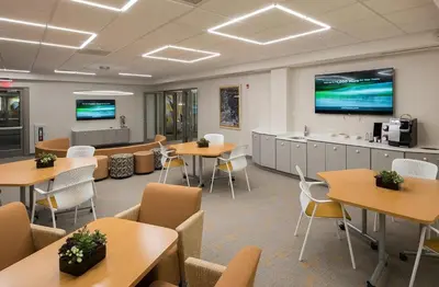 a waiting room with tables and chairs and a large screen at Landing Apartments - Park South in Albany