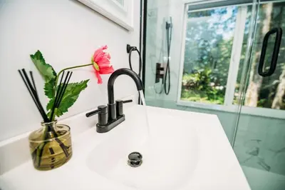 a bathroom sink with a vase with a flower on it at Creekside Family Dreamland - Hot Tub, Firepit, Arcade in Pocono Summit