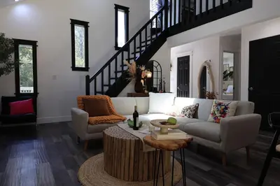 a living room with a couch and a staircase at Creekside Family Dreamland - Hot Tub, Firepit, Arcade in Pocono Summit