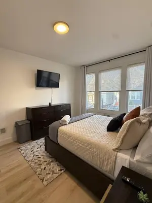 a bedroom with a bed and a flat screen tv at Modern 3BR Home | Chic & Cozy | 30 Min NYC Access in Jersey City