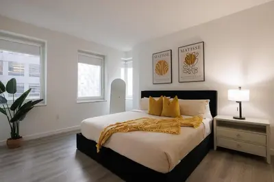 a white bedroom with a large bed with yellow pillows at Elegant NYC Haven Walk to Broadway in New York