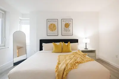 a white bedroom with a large bed with yellow pillows at Elegant NYC Haven Walk to Broadway in New York