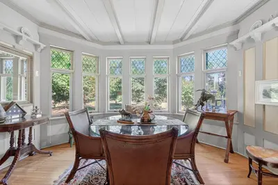 a dining room with a table and chairs and windows at Governors Mansion on the Hudson - Saratoga Riverside Estate in Greenwich