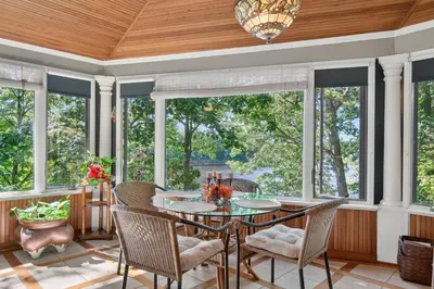 a screened porch with a table and chairs and windows at Governors Mansion on the Hudson - Saratoga Riverside Estate in Greenwich