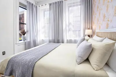 a bedroom with a large bed with white pillows at Classy 2BD Home in Manhattan in New York
