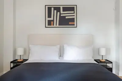 a bedroom with a bed with two lamps and a picture at Blueground Murray Hill fitness center nr Bryant Park NYC-2171 in New York