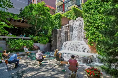 a group of people sitting at tables in front of a fountain at Blueground Midtown East fitness center nr UN NYC-2172 in New York