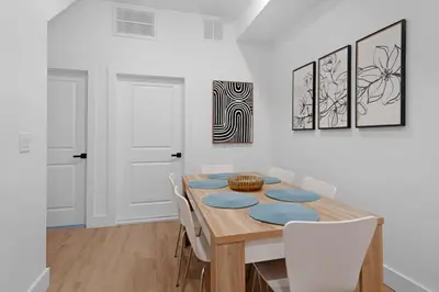 a dining room with a wooden table and white chairs at Spacious Duplex only 15 Minutes to NYC with Firepit Perfect for Groups in Jersey City